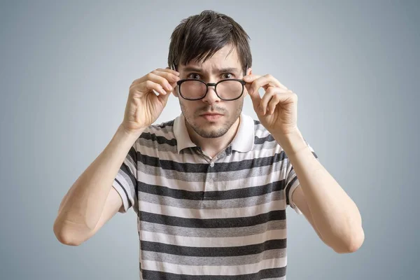 Skeptical or suspicious man is looking at you and touching glasses. — Stock Photo, Image