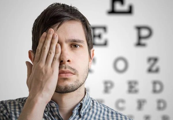 Young man is covering his face with hand and checking his vision — Stock Photo, Image