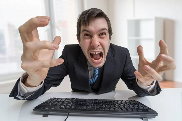 Разочарованный злой бизнесмен кричит и работает с компьютером в офисе . — стоковое фото