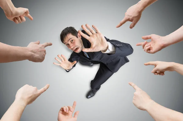Many hands are pointing and blame stressed man. View from top. — Stock Photo, Image