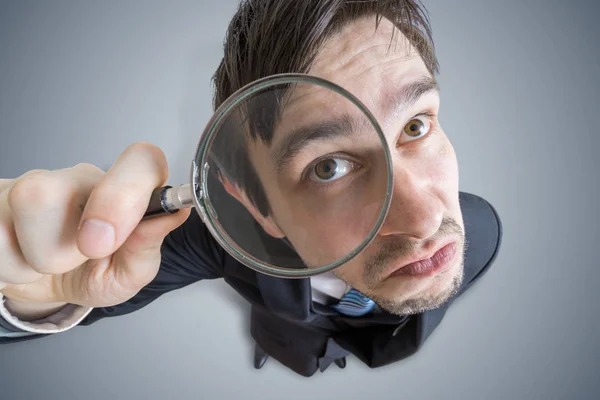 Young man is looking through magnifying glass. View from above. — Stock Photo, Image