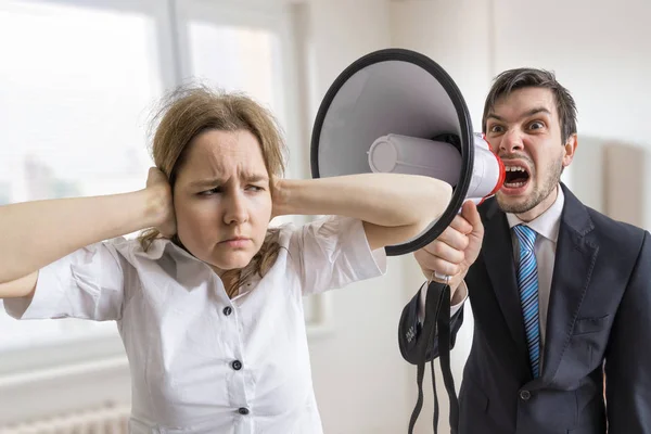 Mobbing at work. Manager is shouting at his secretary at work with megaphone. — Stock Photo, Image