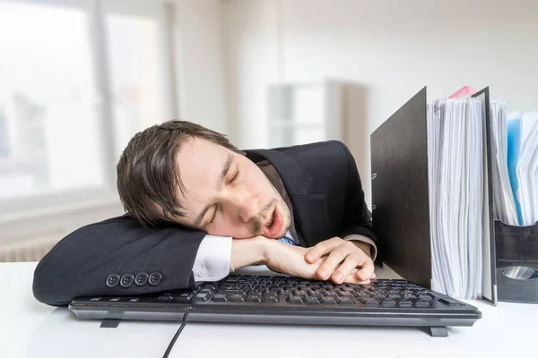 Cansado hombre con exceso de trabajo está durmiendo en el teclado en la oficina en el trabajo . —  Fotos de Stock
