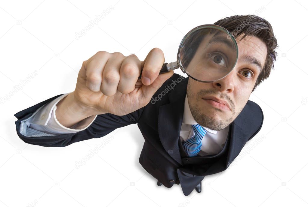 Young man is looking through magnifying glass. Isolated on white
