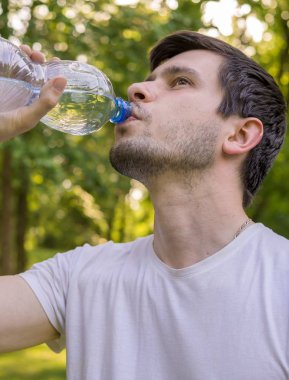 Genç adam içme suyu şişe sıcak güneşli gün.