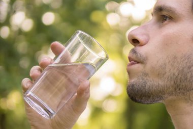 İçme suyu bardaktan güneşli sıcak da, doğada genç adamdır