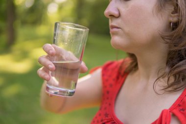 İçme suyu bardaktan doğada güneşli, sıcak genç kadındır 