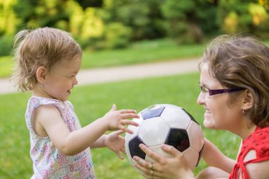 Anne ve kızı ile futbol topu parkta oynarken.