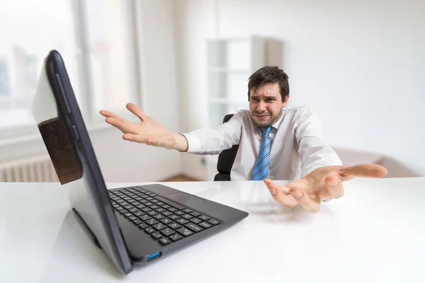 Jovem confuso e inseguro homem está trabalhando com laptop no escritório . — Fotografia de Stock