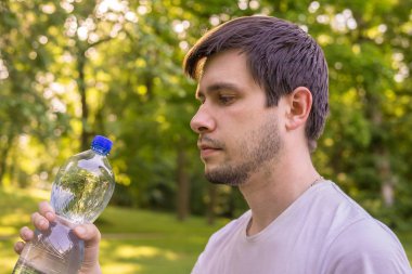 Genç adam su şişesiyle elinde tutan.