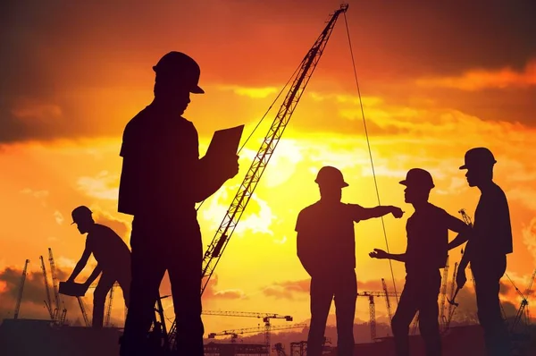 Silhouetten van werknemers die werken op de bouwplaats op suset. — Stockfoto