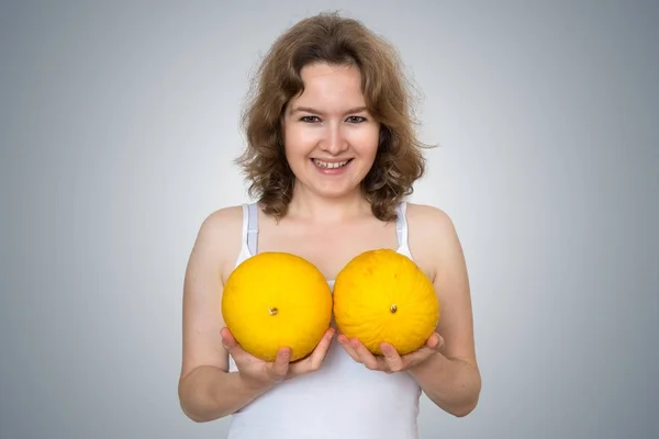 Young beautiful woman holds melons in hands above her breast. Pl — Stock Photo, Image