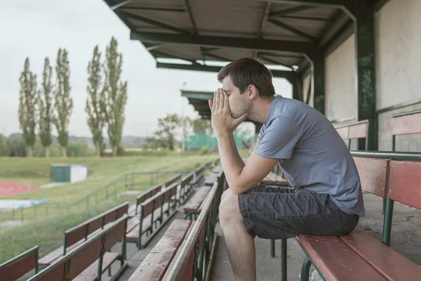 Відчай і пригнічений чоловік сидить на лавці на стадіоні . — стокове фото