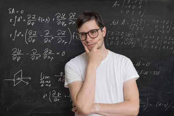 Un joven estudiante está resolviendo el examen de matemáticas. Matemáticas formulado en blac —  Fotos de Stock