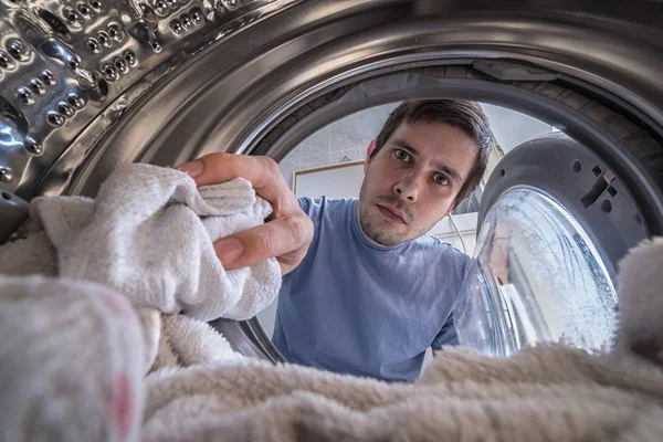Tânărul încarcă rufe în maşină de spălat. Vedere din interior — Fotografie, imagine de stoc