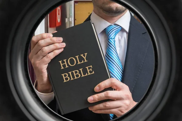 Jehovah witness is showing bible behind door. View from peephole — Stock Photo, Image