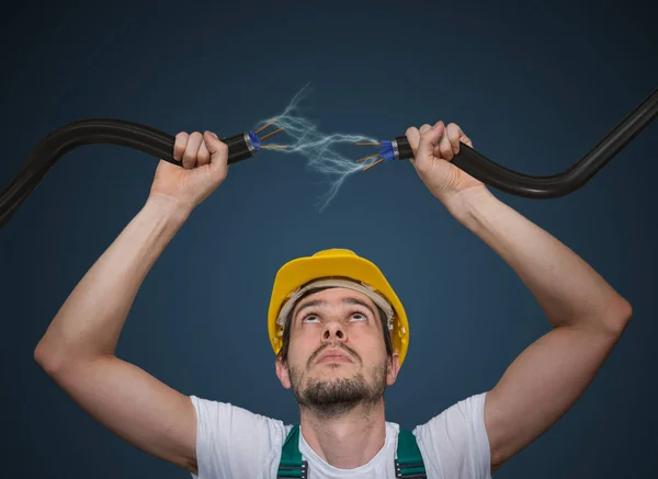 Jovem eletricista segura cabos nas mãos e conectá-los. Lig... — Fotografia de Stock