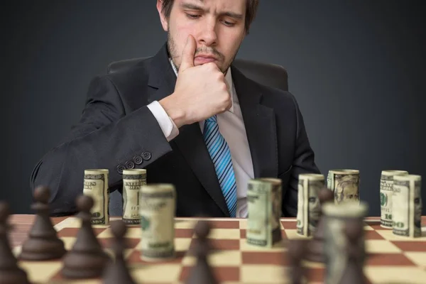 Conceito de estratégia de investimento. Homem está jogando xadrez com dinheiro . — Fotografia de Stock