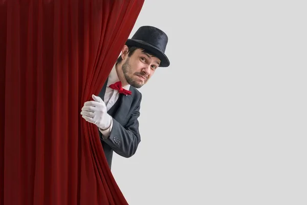 Acteur nerveux ou illusionniste se cache derrière le rideau rouge dans le — Photo