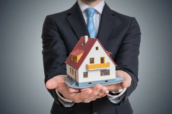 Inmobiliaria está sosteniendo pequeña casa en la mano . —  Fotos de Stock