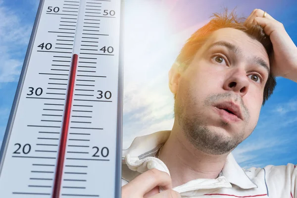 Hot weather concept. Young man is sweating. Thermometer is showing high temperature. Sun in background.