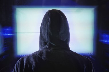Anonim hacker bilgisayar ekranına bakıyor. Arkadan görünüm
