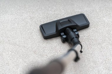 Elektrikli süpürge halıdaki tozu temizliyor. Ev işi kuyruksokumu.