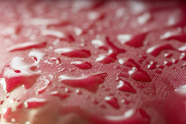 Vista de close-up em gotas de água no tecido impermeável vermelho de umbrell — Fotografia de Stock