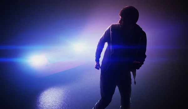 Silhouette of man running away from car on road at night.