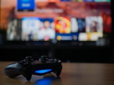 Uk, Jan 2020: Playstation 4 için sony dualshock 4 kumanda kumandası ve arkada koyu renkli TV ekranı