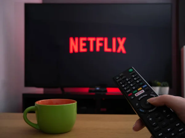 stock image UK, March 2020: TV Television Netflix logo on screen with remote control in home