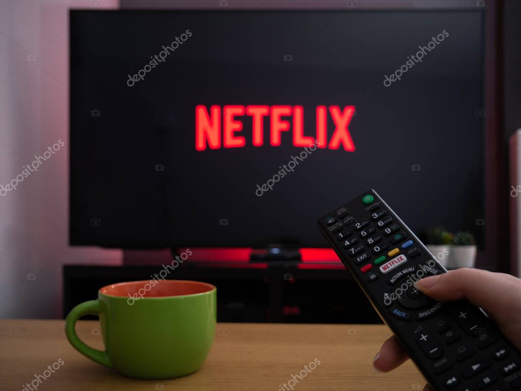 UK, March 2020: TV Television Netflix logo on screen with remote control in home