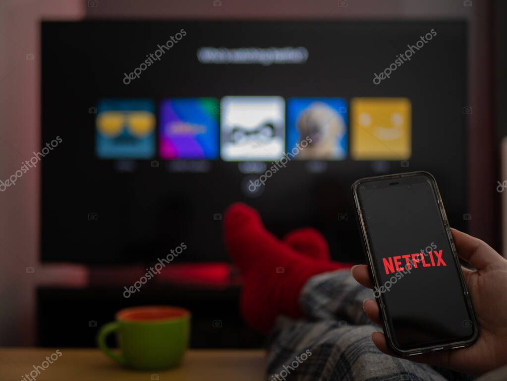 UK, March 2020: TV Television Netflix on phone and tv with feet up comfy