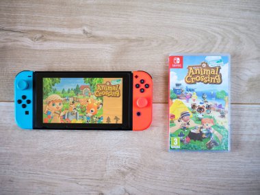 Mayıs 2020, İngiltere: Nintendo oyun konsolu ve hayvan geçişi tahta arka planda yeni ufuklar oyunu