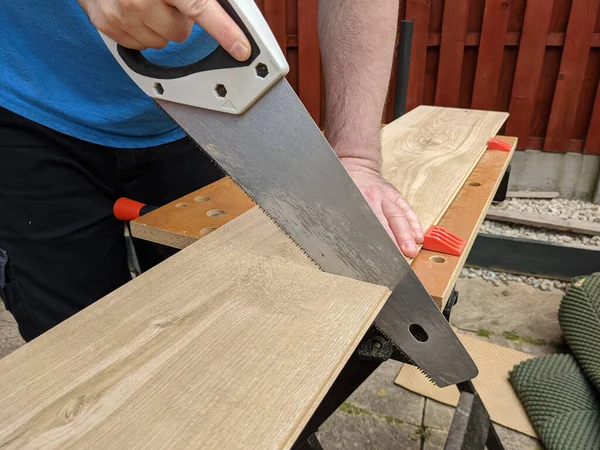 saw cutting laminate floor piece for DIY home improvement on workbench