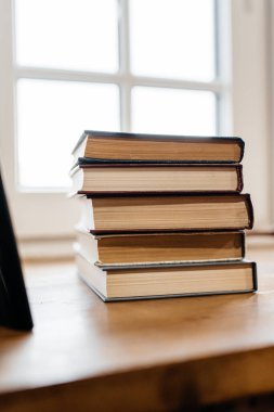 Pencerenin kenarında bir yığın eski kitap var. Yan görünüm