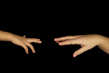Anne ve oğul elleri birbirine uzanıyor. Siyah arka planda soyutlanmış kadın ve çocuklar. Aile ilişkileri, yardım, şefkat ve manevi destek kavramı. Eller yakın plan ve boşluğu kopyala.