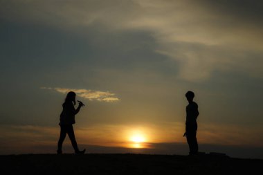 Erkekler ve kadınlar tepenin alacakaranlığında vakit geçirmek için çiftler.