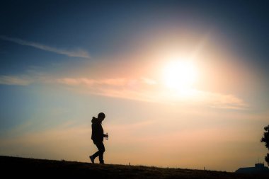 Tepenin alacakaranlığında duran bir adamın silueti