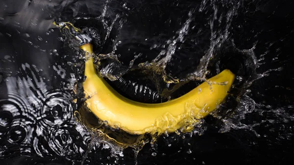 Banaan in plons water op zwarte achtergrond — Stockfoto