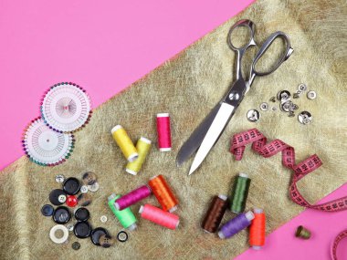 Altın kumaş üzerine bir takım terzilik aletleri ve aksesuarlar. Üst manzara, düz uzanma