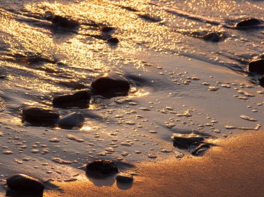 Gün batımında deniz dalgaları ve taşlar