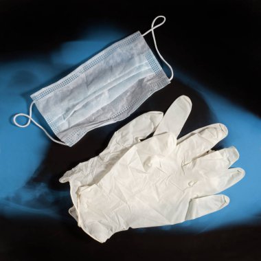Bir çift lateks tıbbi eldiven ve mavi X-ray arka planda kulak ilmiği maskesi. Koruma kavramı