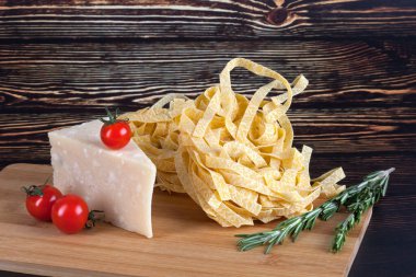 Koyu ahşap arka planda domatesli, peynirli ve biberiyeli İtalyan makarnası. Kopyalama alanı ile