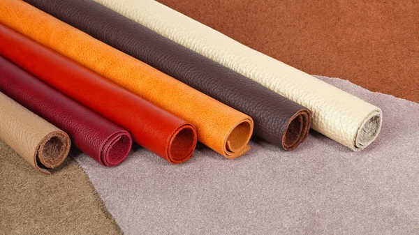 Rolled up different colors natural leather textures samples on leather background