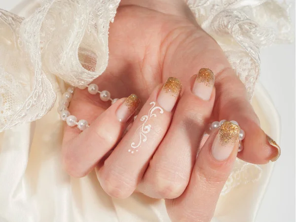 Closeup shot of woman`s hand with golden manicure on white background