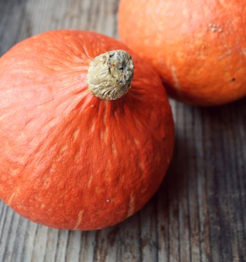 İki küçük organik parlak turuncu kabak ahşap arka plan üzerinde