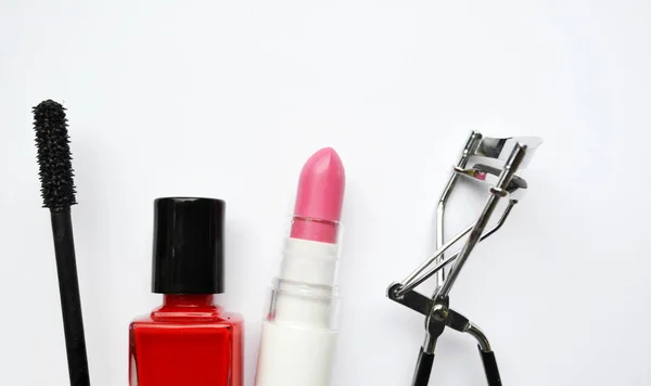 Kosmetyki z tusz do rzęs czarny, różowy i czerwony lakier do paznokci i szminka i rzęs curlerka na białym tle — Zdjęcie stockowe