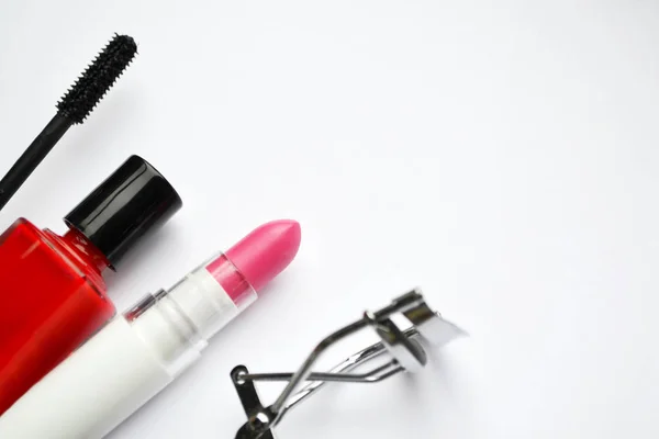Set de cosméticos con rímel negro, esmalte de uñas rosa y rojo y lápiz labial y rizador de pestañas aislado en blanco —  Fotos de Stock