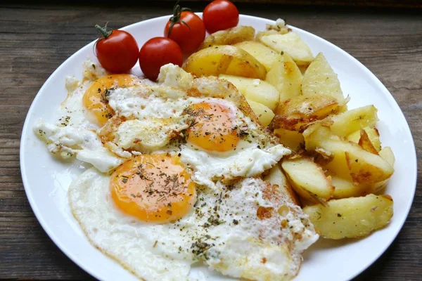 Grote ronde plaat vol met gebakken eieren, patat en cherry tomaten - een traditionele continentaal ontbijt — Stockfoto